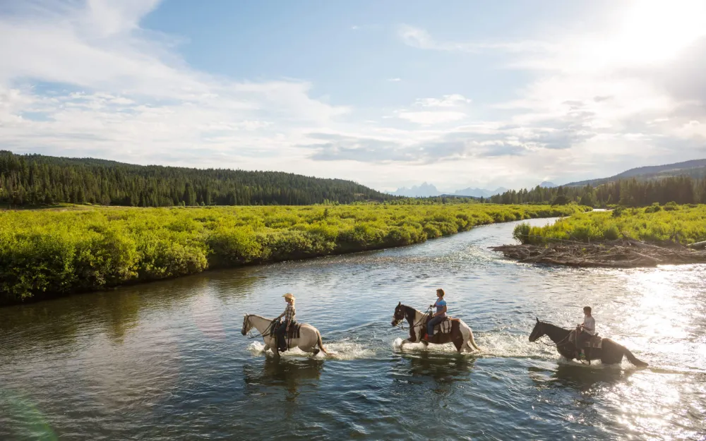 Cinematic aerial shot of riders crossing a river